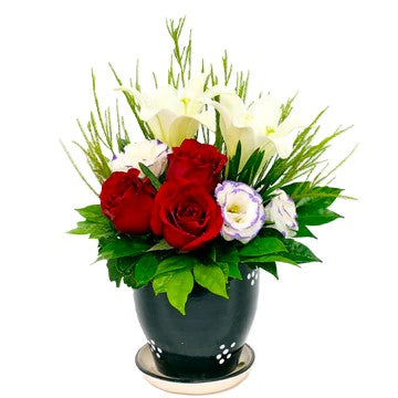 Red roses, white lilies and eustoma in a vase table flower arrangement
